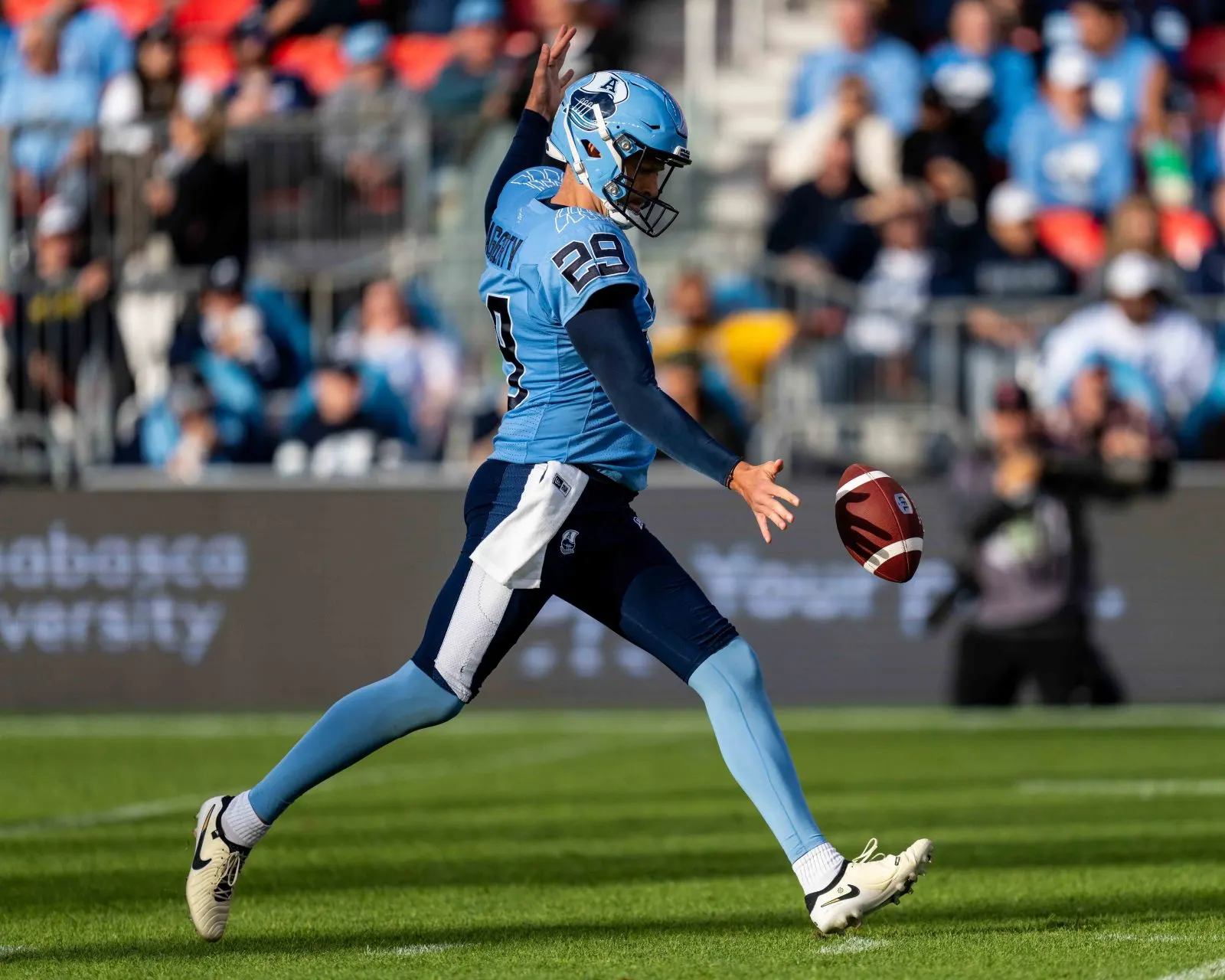 Professional punter in mid-strike under stadium lights